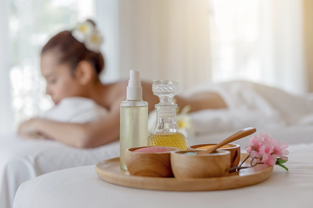 Spa and massage elements, aroma salt, herbal oil, Young woman relaxing in background, Spa treatment and aromatherapy concept, Selective focus